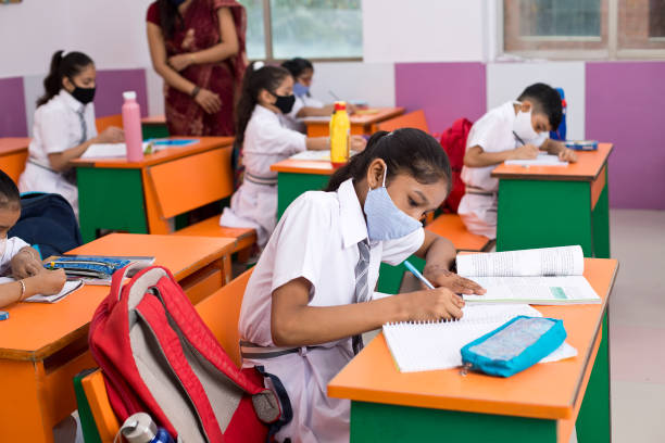 Students in classroom wearing protective face mask after school reopening